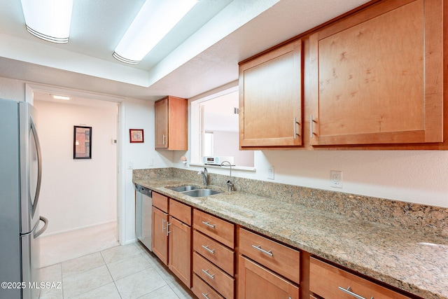 kitchen featuring stainless steel appliances, light tile patterned flooring, a sink, and light stone counters