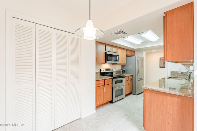 kitchen featuring stainless steel appliances, a sink, visible vents, light stone countertops, and brown cabinetry