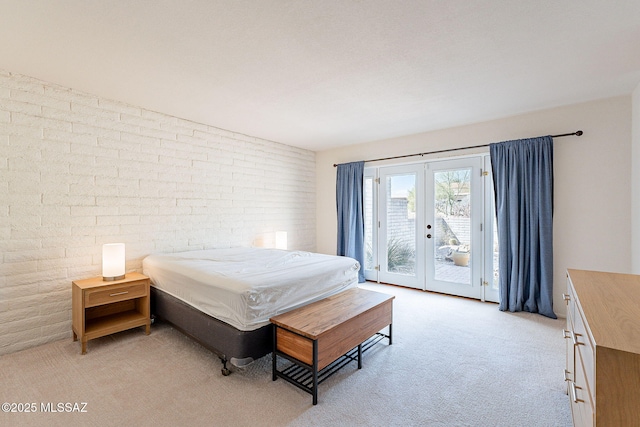 bedroom with access to outside, french doors, brick wall, and light colored carpet