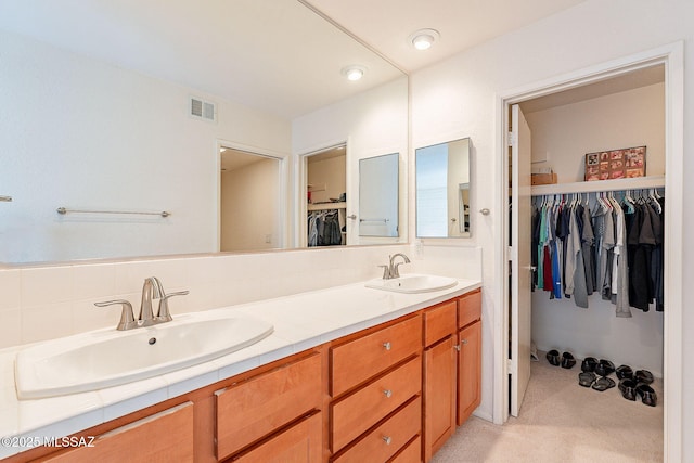 full bath with visible vents, a sink, a spacious closet, and double vanity