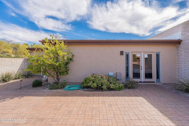 exterior space featuring a patio area, fence, french doors, and stucco siding