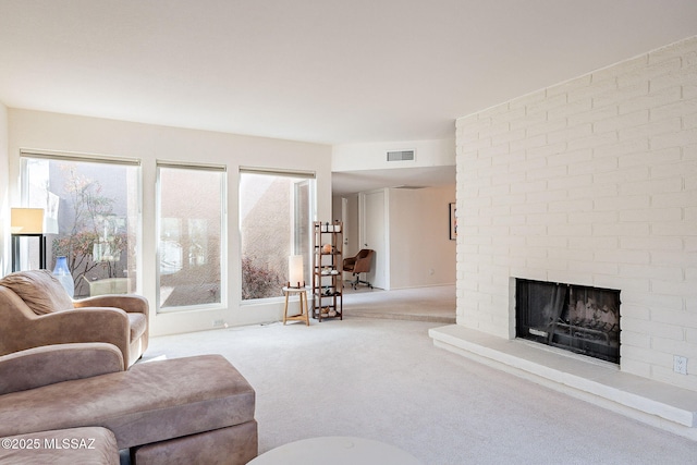 carpeted living area with a brick fireplace and visible vents