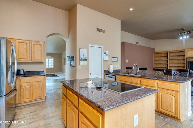 kitchen featuring dark stone countertops, stainless steel appliances, a kitchen island, sink, and kitchen peninsula