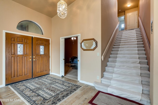 foyer featuring light hardwood / wood-style floors, a chandelier, and a high ceiling