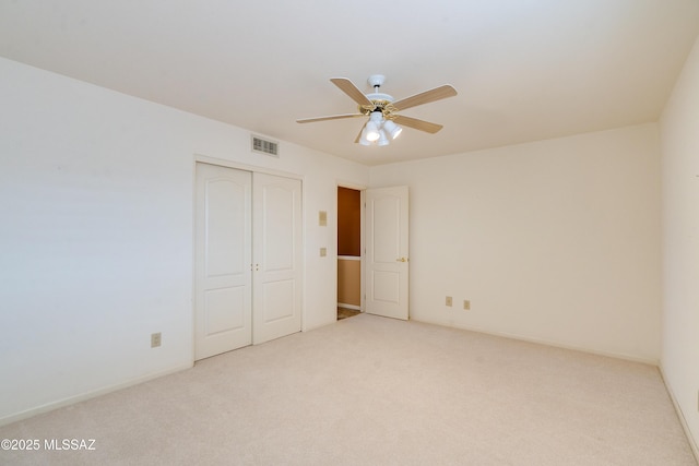 unfurnished bedroom featuring ceiling fan, light carpet, and a closet