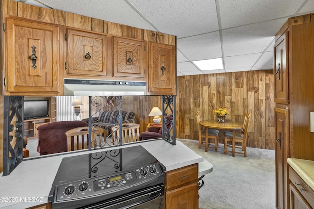 kitchen featuring black range with electric stovetop, a paneled ceiling, light carpet, and wooden walls