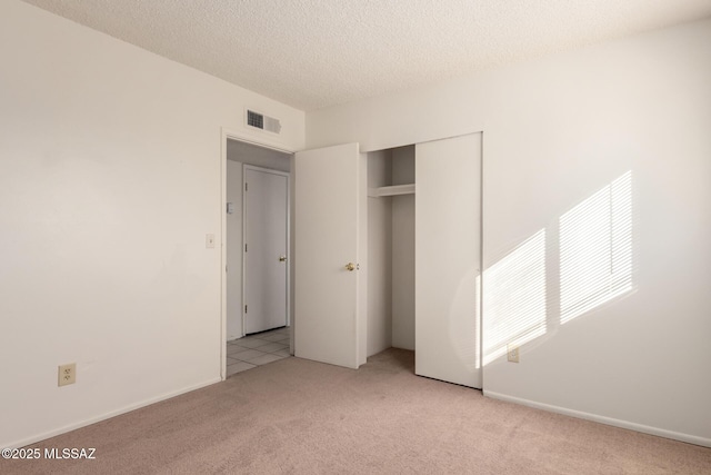 unfurnished bedroom with light carpet, a closet, and a textured ceiling