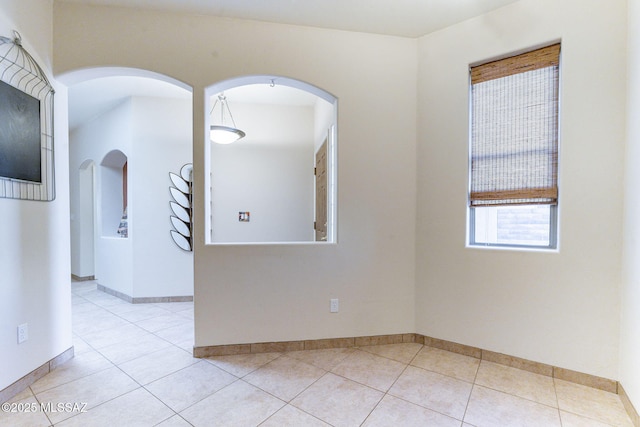 spare room featuring light tile patterned floors and baseboards