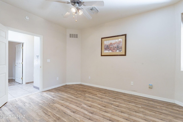 spare room with light wood finished floors, baseboards, visible vents, and a ceiling fan