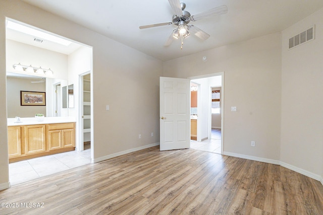 unfurnished bedroom with light wood-type flooring, baseboards, visible vents, and connected bathroom