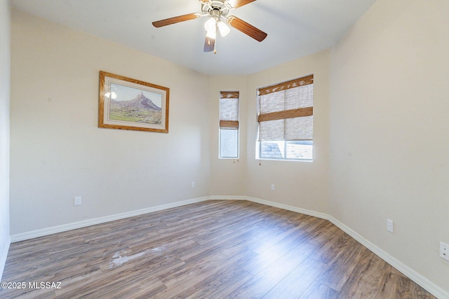 spare room featuring wood finished floors, a ceiling fan, and baseboards