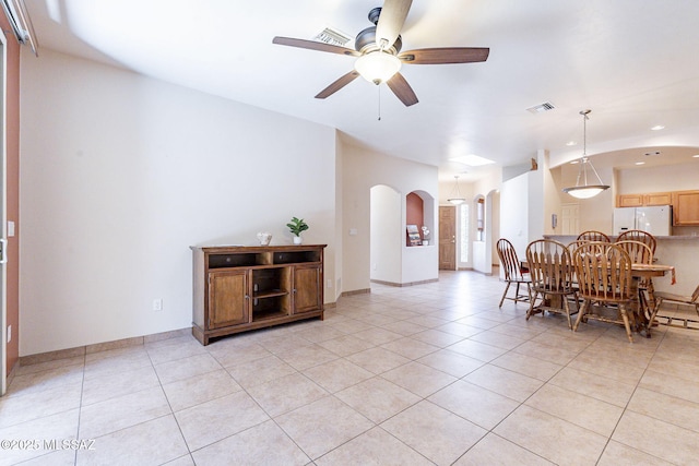 dining space featuring arched walkways, light tile patterned floors, a ceiling fan, visible vents, and baseboards