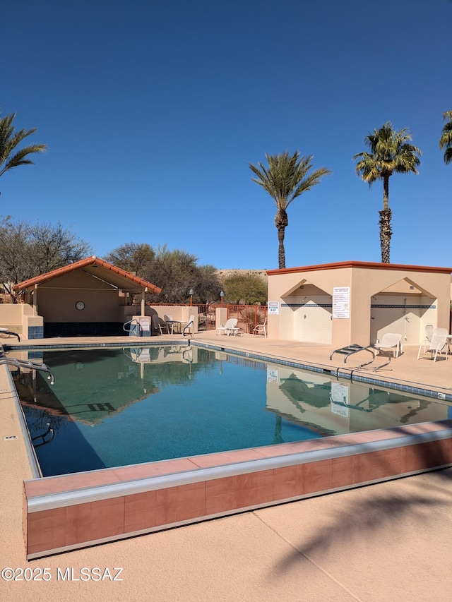 pool with a patio area and fence