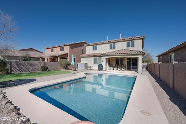 rear view of property with a fenced in pool and a patio