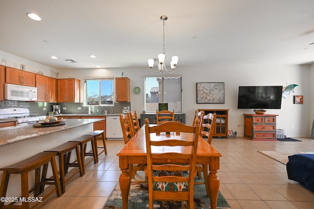 dining space with light tile patterned floors, a notable chandelier, and sink