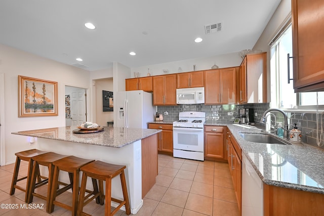 kitchen with sink, white appliances, a breakfast bar area, and a kitchen island