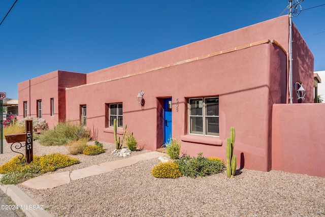 pueblo-style house featuring fence and stucco siding