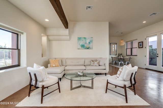 living room featuring concrete flooring, beam ceiling, and french doors