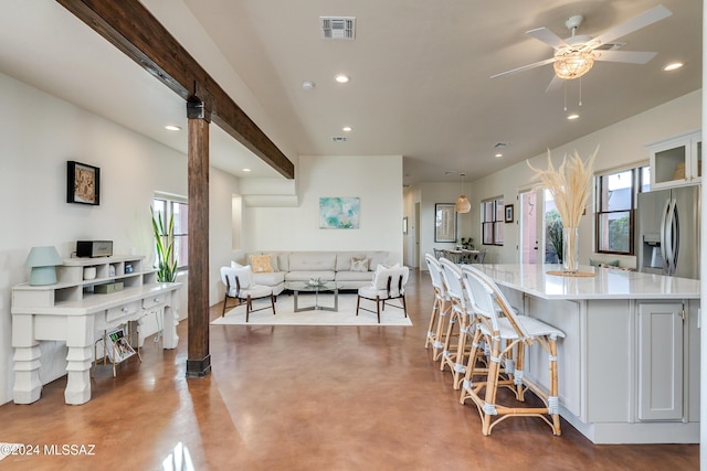 kitchen with stainless steel refrigerator with ice dispenser, white cabinetry, a center island, and concrete floors