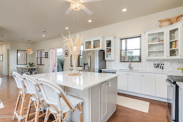 kitchen featuring appliances with stainless steel finishes, sink, white cabinets, hanging light fixtures, and a center island