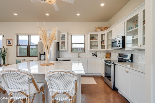 kitchen with a kitchen bar, sink, white cabinets, stainless steel appliances, and backsplash