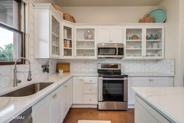 kitchen featuring sink, light stone counters, appliances with stainless steel finishes, white cabinets, and backsplash