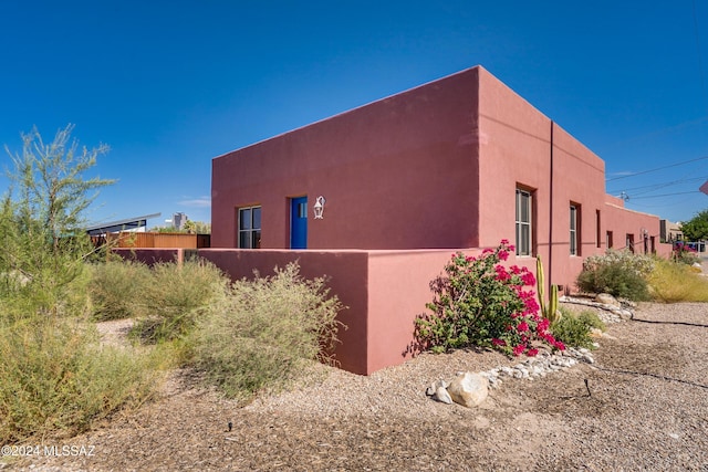 view of side of home with fence and stucco siding