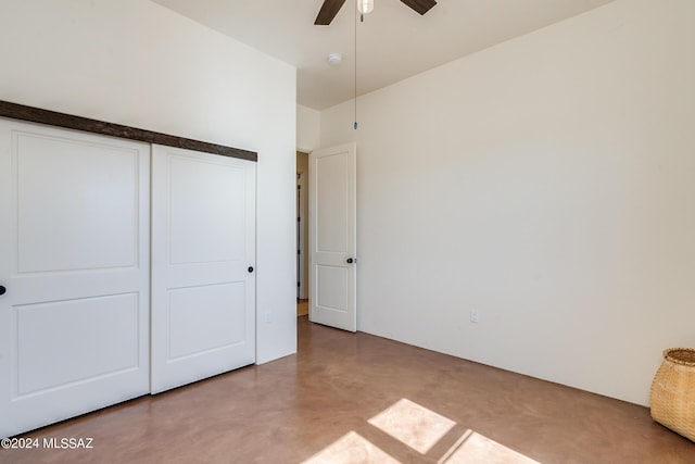 unfurnished bedroom with concrete flooring, a closet, and ceiling fan