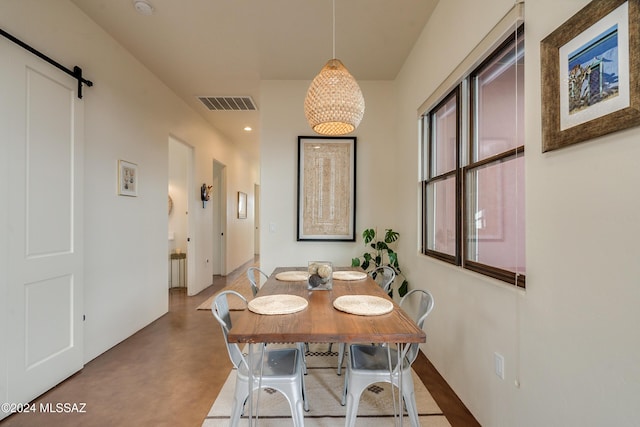 dining room featuring a barn door and concrete floors