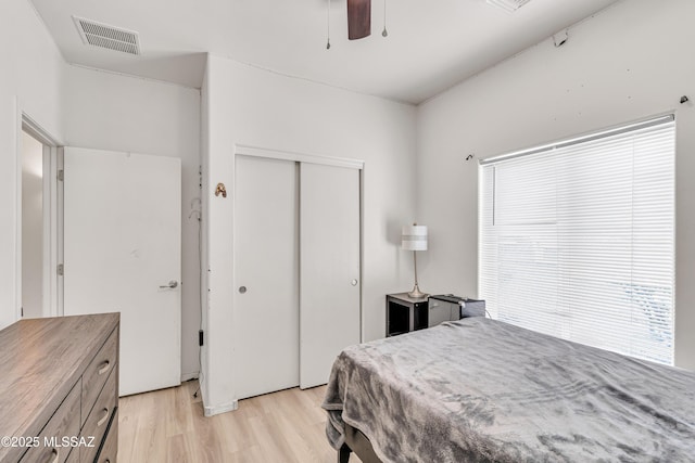 bedroom with multiple windows, ceiling fan, a closet, and light hardwood / wood-style flooring