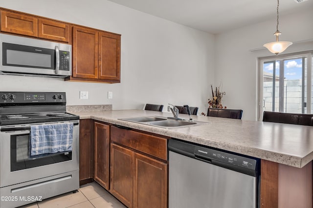 kitchen with sink, decorative light fixtures, light tile patterned floors, appliances with stainless steel finishes, and kitchen peninsula