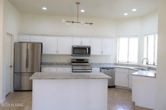 kitchen featuring appliances with stainless steel finishes, white cabinets, a kitchen island, a sink, and light tile patterned flooring