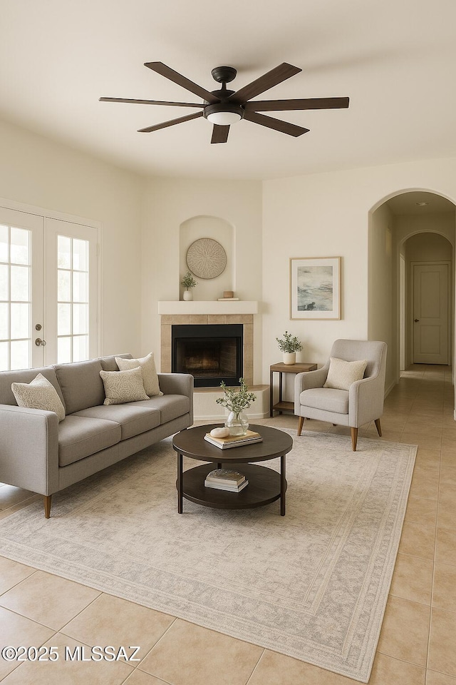 533 N Kino Springs Dr, Nogales, AZ 85621 - living room featuring arched walkways, light tile patterned floors, a ceiling fan, french doors, and a fireplace