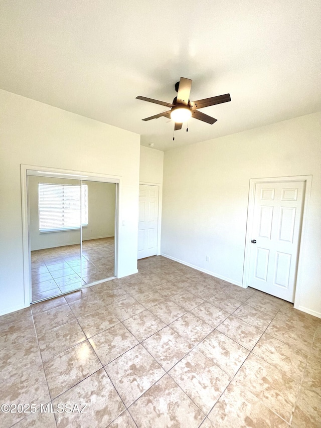 unfurnished bedroom featuring a ceiling fan, a closet, baseboards, and light tile patterned floors