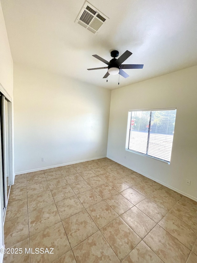 spare room with a ceiling fan, visible vents, baseboards, and light tile patterned floors