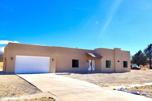 southwest-style home with driveway, an attached garage, and stucco siding