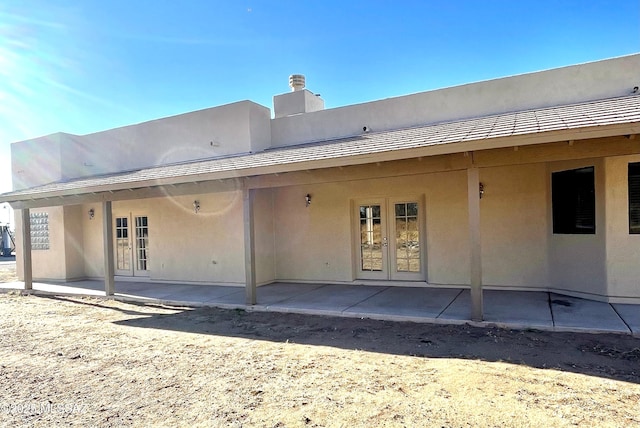 rear view of property featuring french doors, a patio, and stucco siding