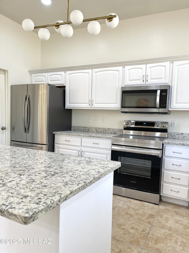 kitchen featuring appliances with stainless steel finishes, light tile patterned flooring, white cabinetry, and light stone countertops