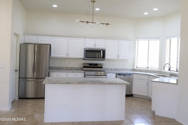 kitchen featuring a center island, light tile patterned floors, appliances with stainless steel finishes, white cabinets, and a sink