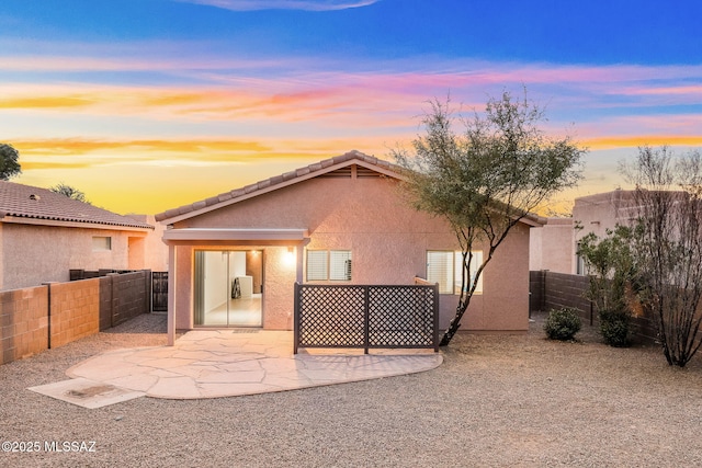 back house at dusk with a patio area