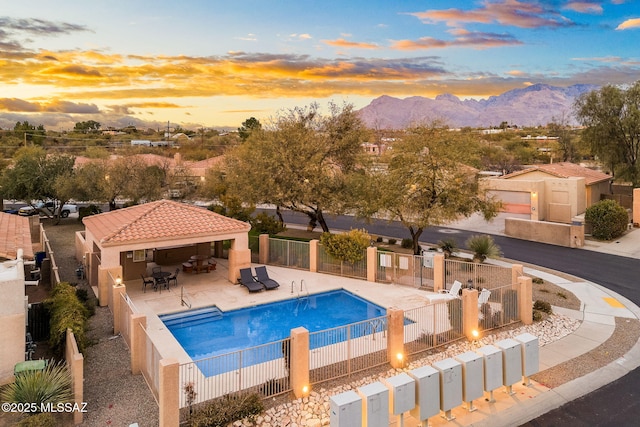 pool at dusk featuring a mountain view, a gazebo, and a patio