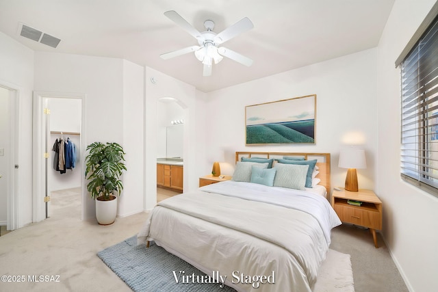 carpeted bedroom with ceiling fan, a walk in closet, a closet, and ensuite bath