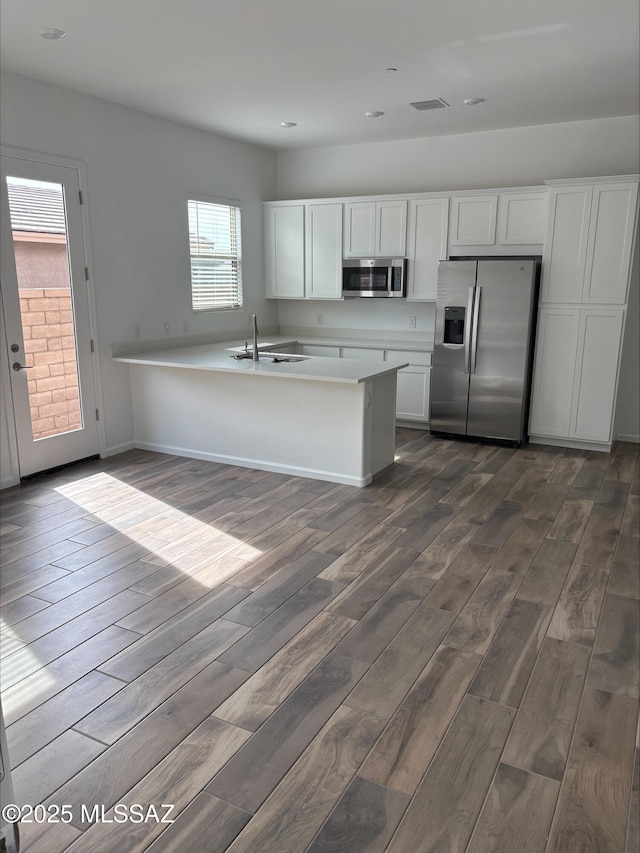 kitchen featuring dark wood-style flooring, white cabinets, stainless steel appliances, and visible vents