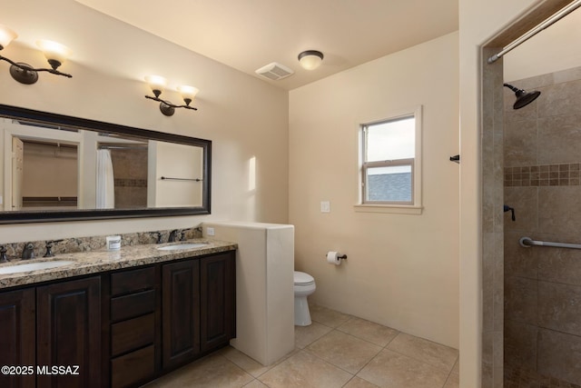 bathroom with tile patterned floors, vanity, toilet, and a tile shower