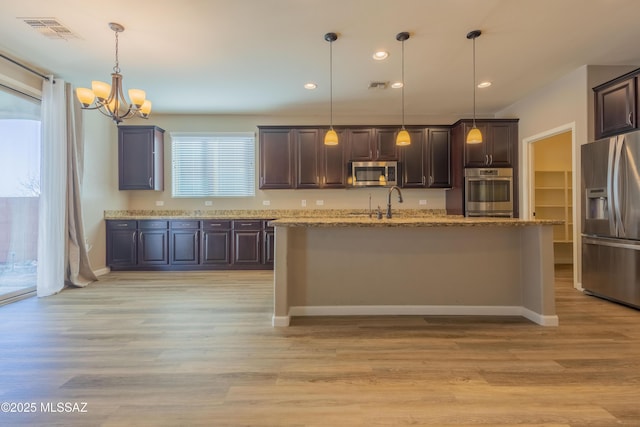 kitchen with stainless steel appliances, hanging light fixtures, light wood-type flooring, and dark brown cabinetry