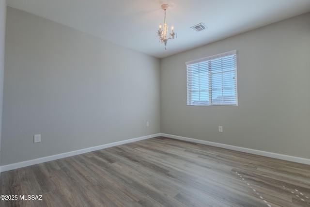 unfurnished room featuring hardwood / wood-style floors and an inviting chandelier