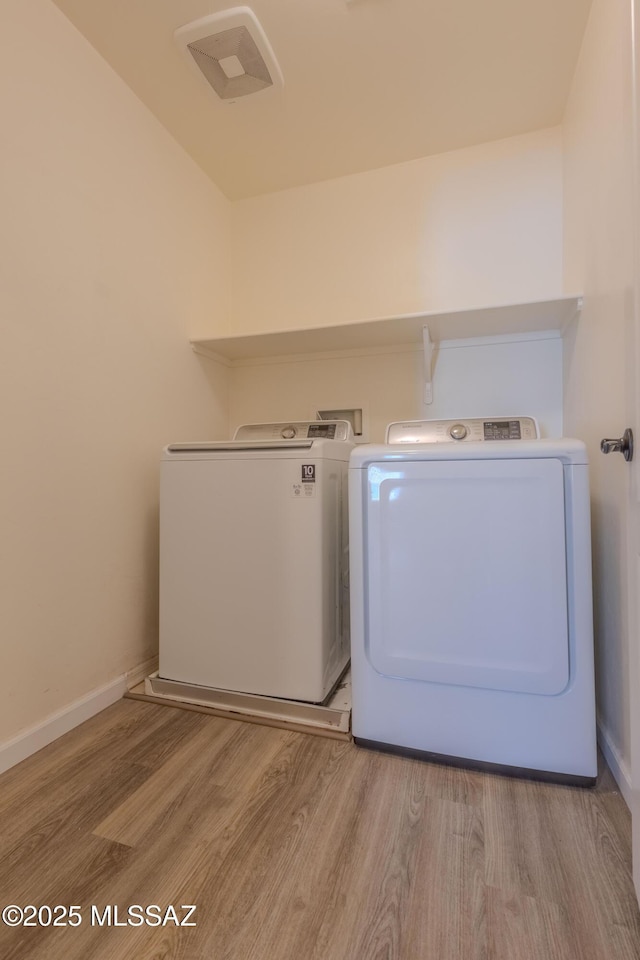 laundry area with washer and dryer and light hardwood / wood-style flooring