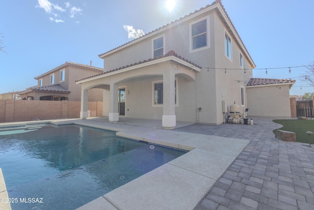 rear view of house with a fenced in pool and a patio