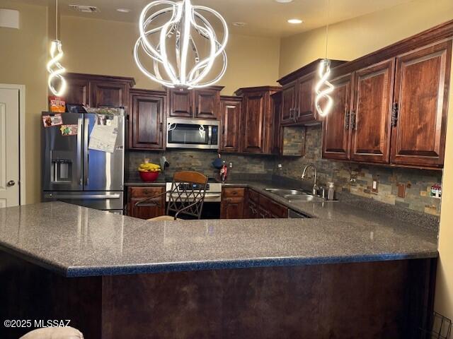 kitchen featuring appliances with stainless steel finishes, sink, decorative backsplash, hanging light fixtures, and a notable chandelier