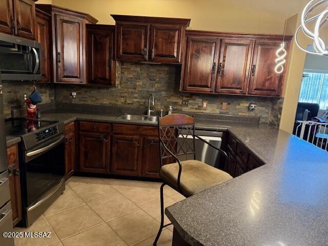 kitchen with light tile patterned flooring, appliances with stainless steel finishes, sink, and decorative backsplash